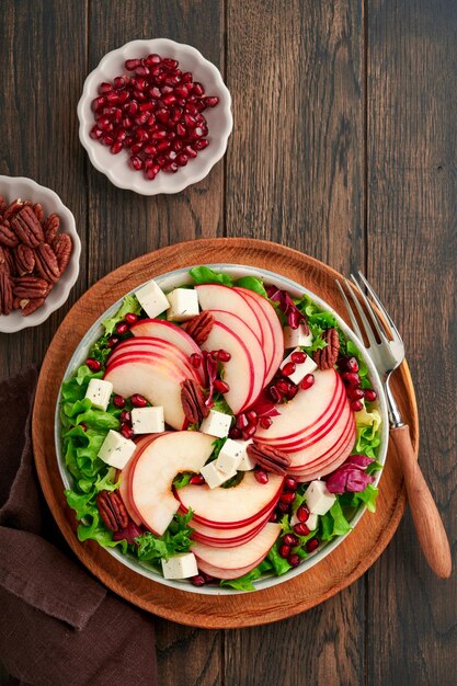 Salad Fresh fruit green salad with feta cheese apple pomegranate pecan and lettuce on white plate Idea for healthy delicious winter Christmas salad Healthy balanced eating Top view