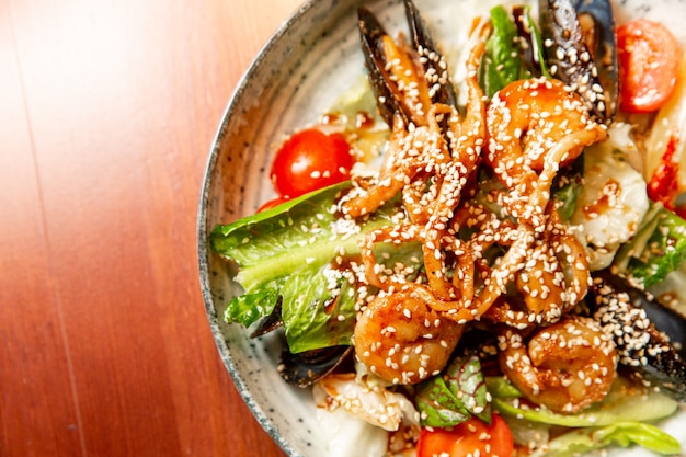 Salad of fresh seafood mussels shrimp fresh vegetables and greens on a wooden background