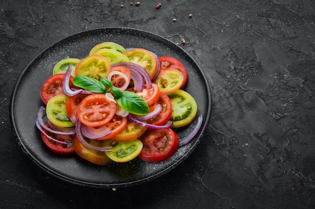 검정 접시에 있는 신선한 토마토와 양파 샐러드 오래된 배경 상단 보기 텍스트를 위한 여유 공간