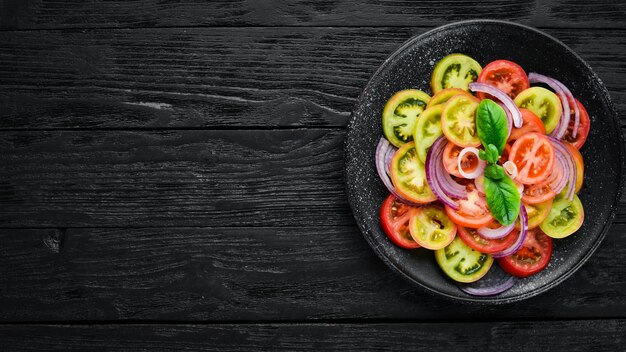 검정 접시에 있는 신선한 토마토와 양파 샐러드 오래된 배경 상단 보기 텍스트를 위한 여유 공간