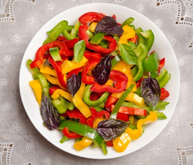 Salad from bell pepper and basil in a porcelain plate on the tablecloth