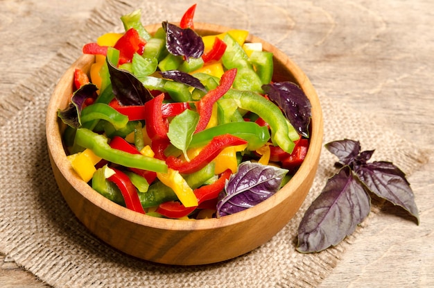 Salad from bell pepper and basil on wooden background