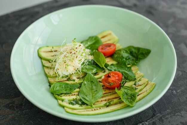 Salad from zucchini slices with cherry tomato, cream cheese and micro greens. Vegetarian food