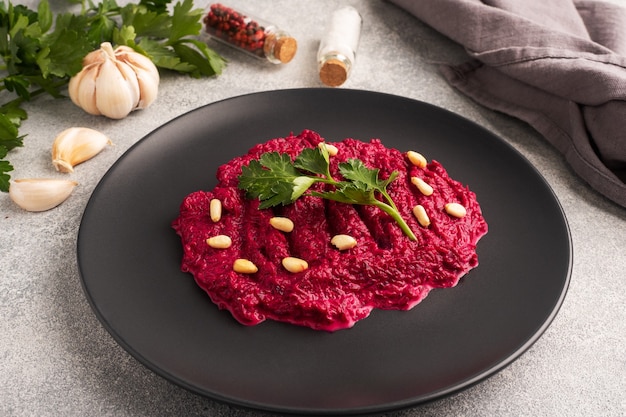 Salad of grated beetroot pine nuts and parsley with cream sauce on a plate.