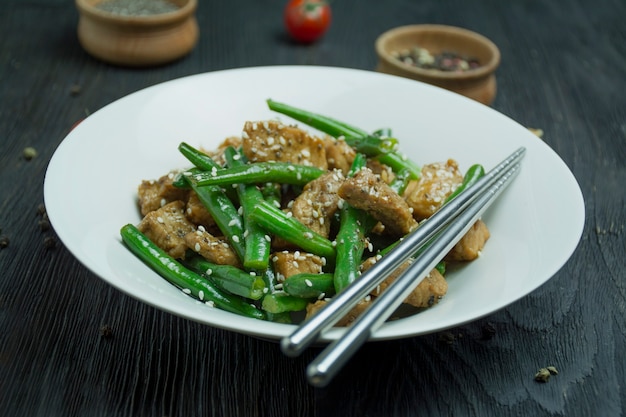 Salad of green beans and meat, sprinkled with sesame seeds.