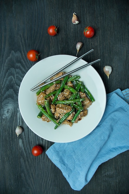 Salad of green beans and meat, sprinkled with sesame seeds.