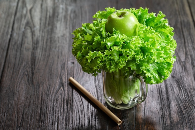 Salad leaves, green apple in a jar mug on wooden table ready to cook healthy smoothie