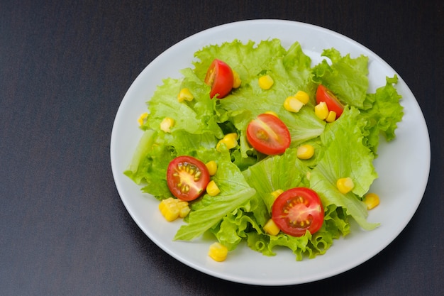 Salad of lettuce and  cherry tomato,orange,corn in white dish.Concept for a tasty and healthy meal.vegetarian food concept