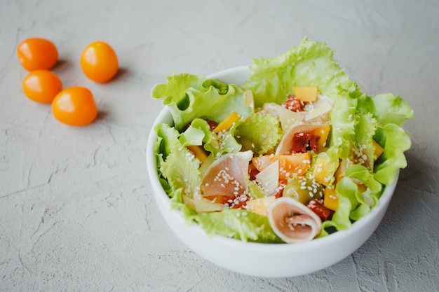 Salad of lettuce, cherry tomatoes, olives, sun-dried tomatoes, Parma ham