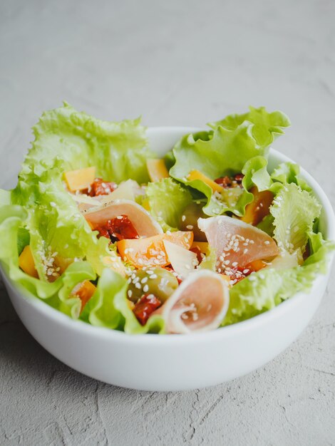 Salad of lettuce, tomatoes, olives, sun-dried tomatoes, Parma ham, cheddar