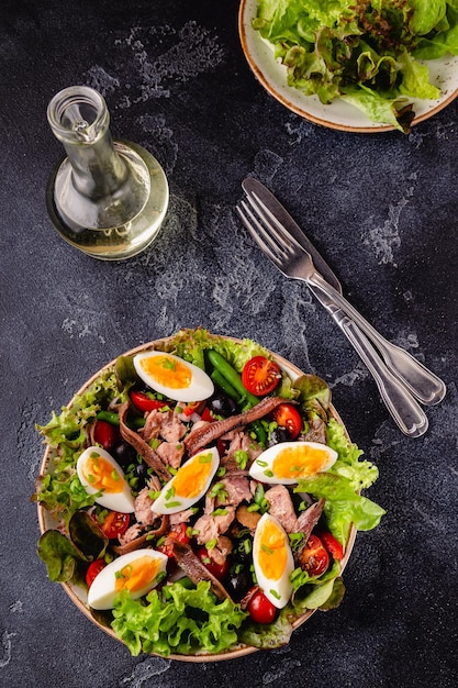 Фото Салат нисуаз с яйцами тунца, зеленой фасолью, помидорами, оливками, салатом и анчоусами