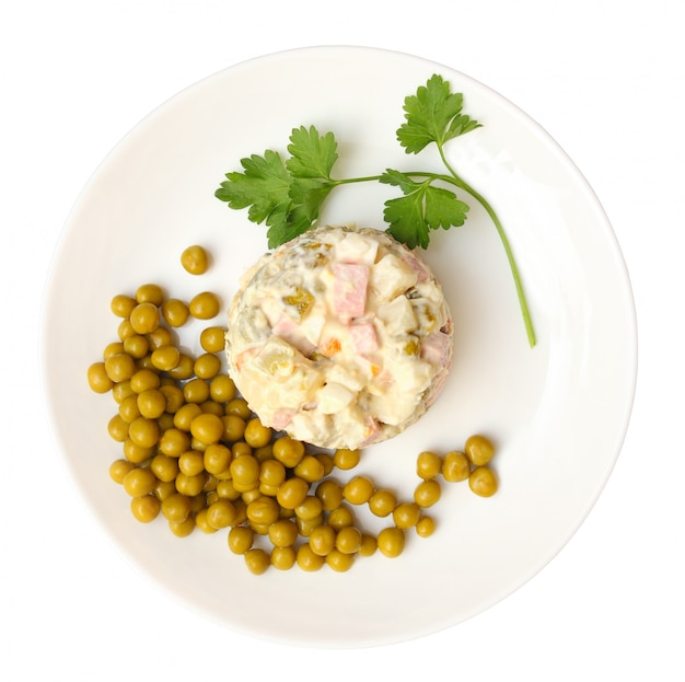 Salad olivier, green peas on a plate isolated on white background with clipping path. Top view.