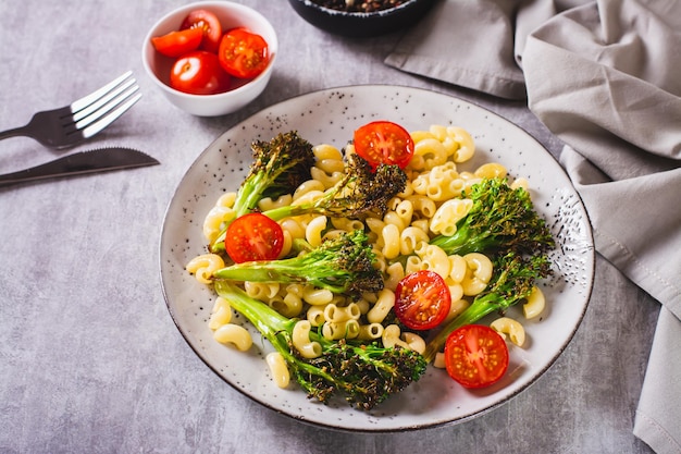 Salad of pasta tomatoes and fried broccoli sprouts on a plate on the table