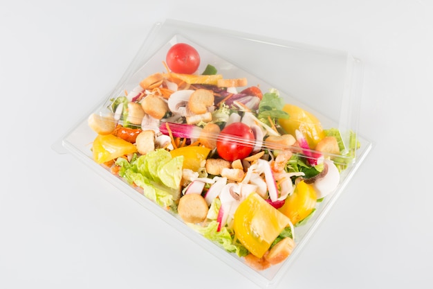 Salad in a plastic take away box isolated on white