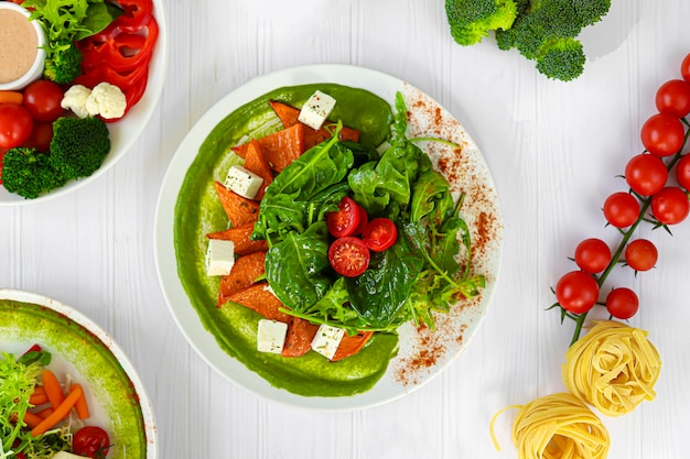 Photo salad of pumpkin spinach feta cheese and cherry tomatoes topped with sauce keto diet