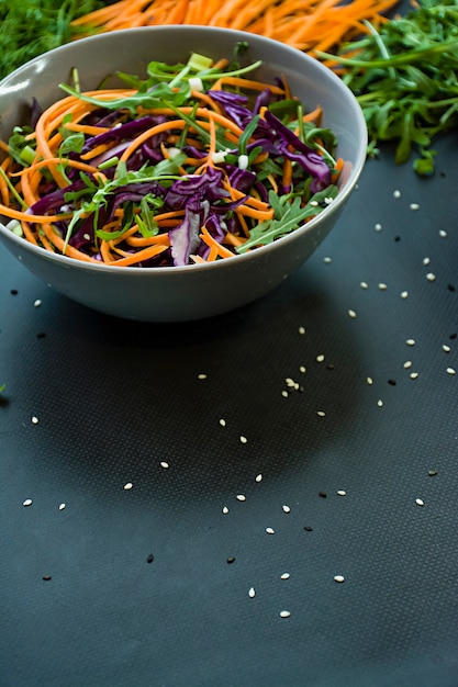 Salad of red cabbage, carrots and greens. Decorated with sliced vegetables and herbs.