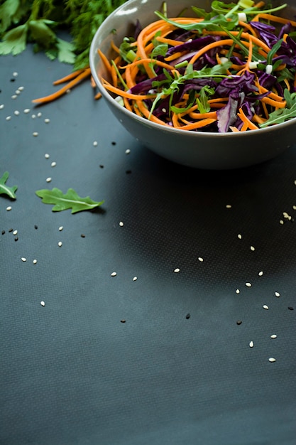 Salad of red cabbage, carrots and greens. Decorated with sliced vegetables and herbs.