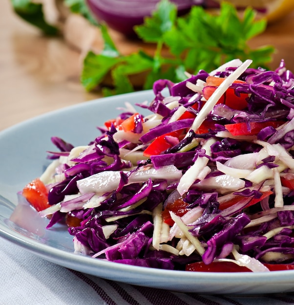 Salad of red and white cabbage and sweet red pepper, seasoned with lemon juice and olive oil in wooden bowl