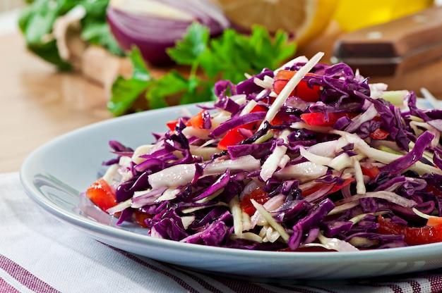 Salad of red and white cabbage and sweet red pepper, seasoned with lemon juice and olive oil in wooden bowl