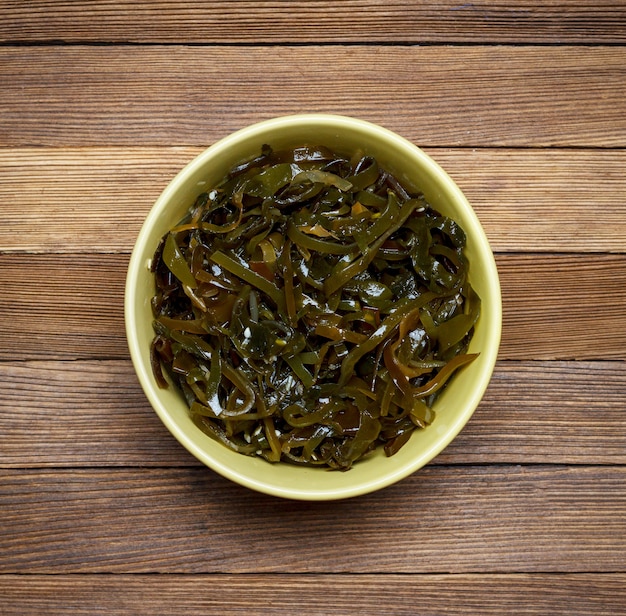 Salad of sea cabbage and sesame on a brown wooden background top view close-up