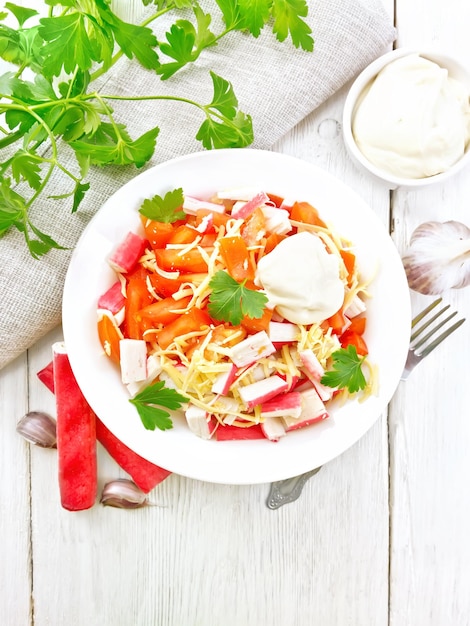 Salad of surimi and tomatoes on light board top