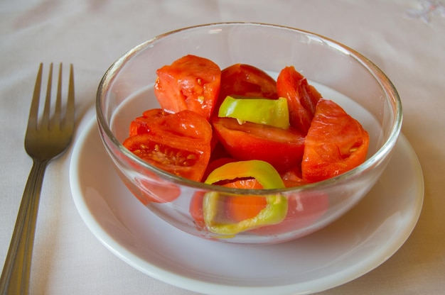 Салат из помидоров и сладкого перца в стеклянной миске с вилкой
