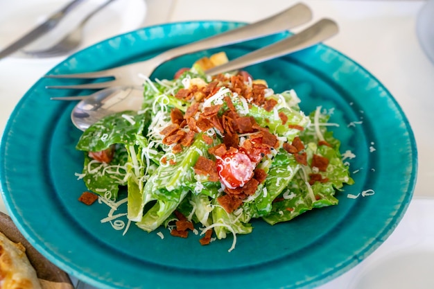 Foto condimento per insalata con pancetta in piatto verde blu vintage