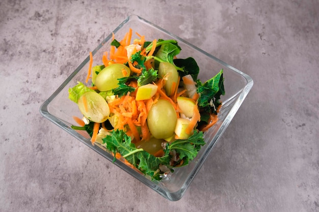 Salad vegetable and fruit mix in transparent bowl on gray surface