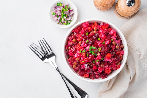 Salad vinaigrette with boiled vegetables, sauerkraut, cucumbers and peas on a light background. Traditional Russian salad with beetroot. Top view.