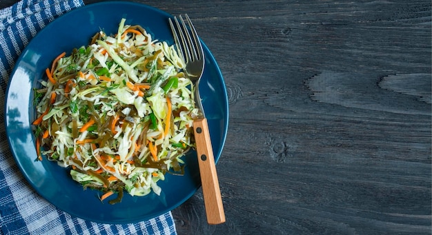 木製のテーブルの上のプレートに白菜海藻ニンジンとハーブのサラダ 新鮮な野菜のサラダ 食べ物の背景 ベジタリアン料理 上からの眺め コピースペース