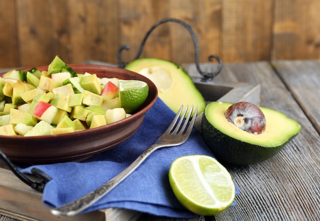 Photo salad with apple and avocado in bowl on tray on table close up