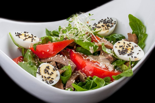 Salad with arugula and beef tongue with tomatoes and egg