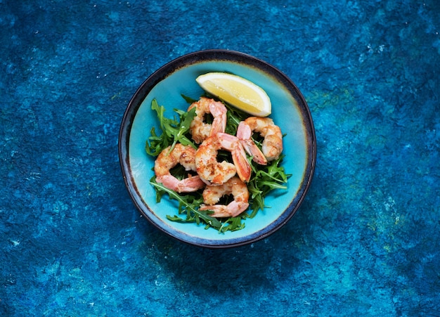 Salad with arugula and fried shrimp. Seafood  balanced clean eating, top view. Healhty lunch bowl.