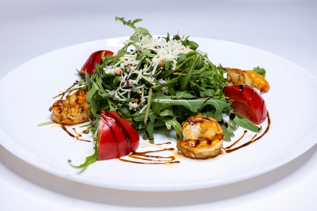 Salad with arugula and grilled shrimps on a white plate and white backgtound mediterranean national