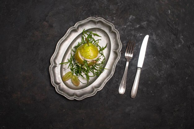 Salad with arugula stracciatella nuts grapes and honey in pear on metal plate on black background