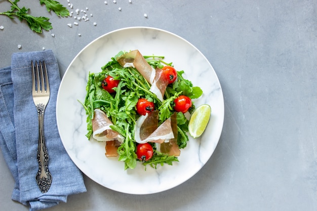 Photo salad with arugula, tomatoes and prosciutto.