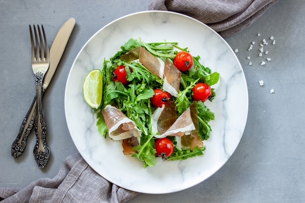 Salad with arugula, tomatoes and prosciutto.