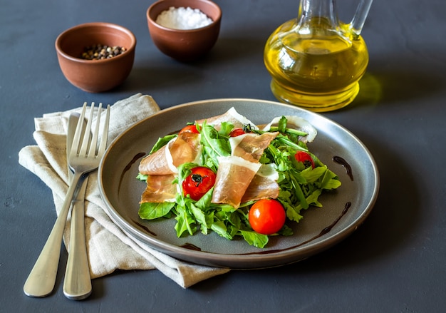 Салат с рукколой, помидорами и прошутто.