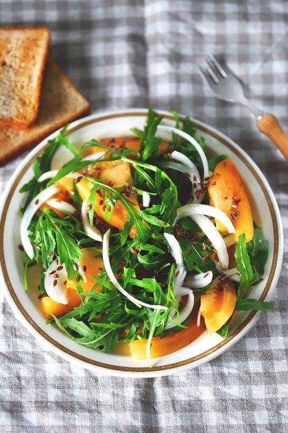 Salad with arugula and yellow tomato on a plate.