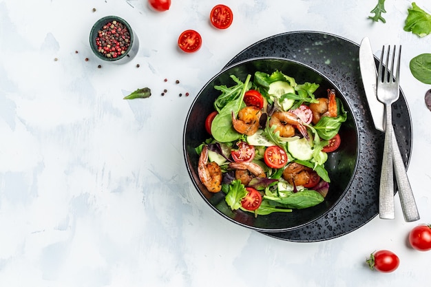 Salad with avocado and shrimps in bowl, Delicious breakfast or snack on a light background, top view.