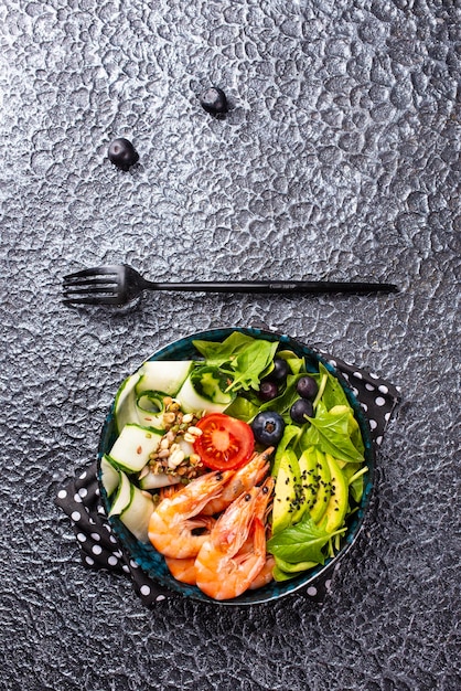 Salad with avocado and shrimps in bowl selective focus