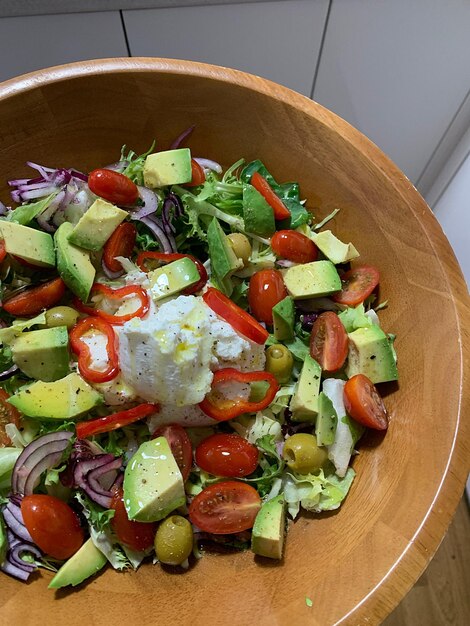 Salad with avocado tomatoes olives red onion and mozzarella colorful spring salad plate of chopped vegetables healthy food