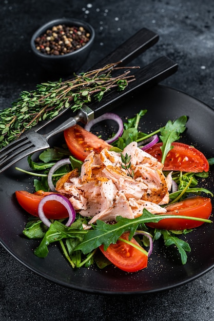 구운 연어 필렛 스테이크, 신선한 arugula, 토마토를 접시에 담은 샐러드.