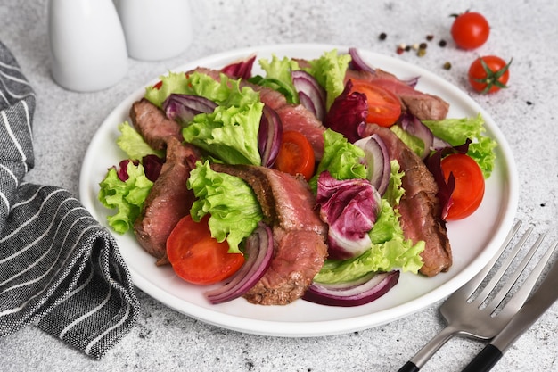 Salad with beef lettuce and tomatoes on a concrete background