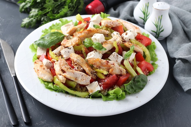 Salad with bulgur, baked chicken, bell pepper, basil and feta on white plate