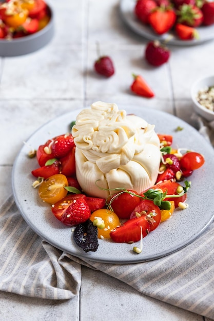 Salad with burrata cheese cherry tomatoes and strawberry with microgreen and olive oil Keto diet