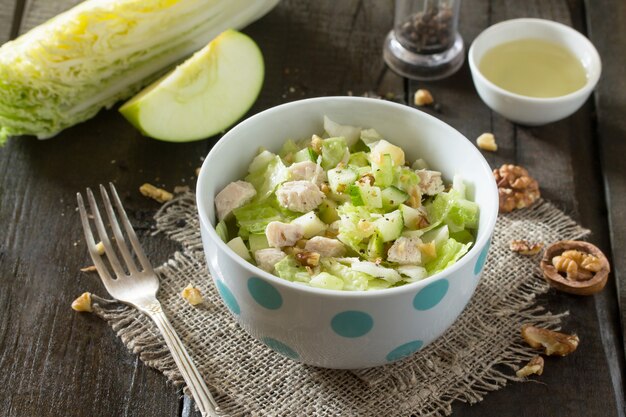 Salad with cabbage, chicken, apple, cucumber, and walnuts