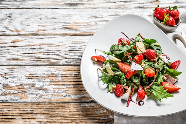 Salad with Camembert, strawberries, nuts, chard and arugula. White background. Top view. Copy space