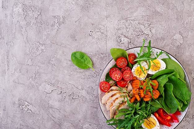 Salad with cherry tomatoes, chicken breast, eggs, carrot, arugula and spinach