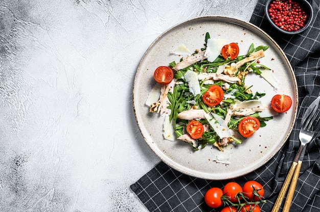 Salad with chicken, arugula, walnuts, tomatoes and Parmesan. gray background